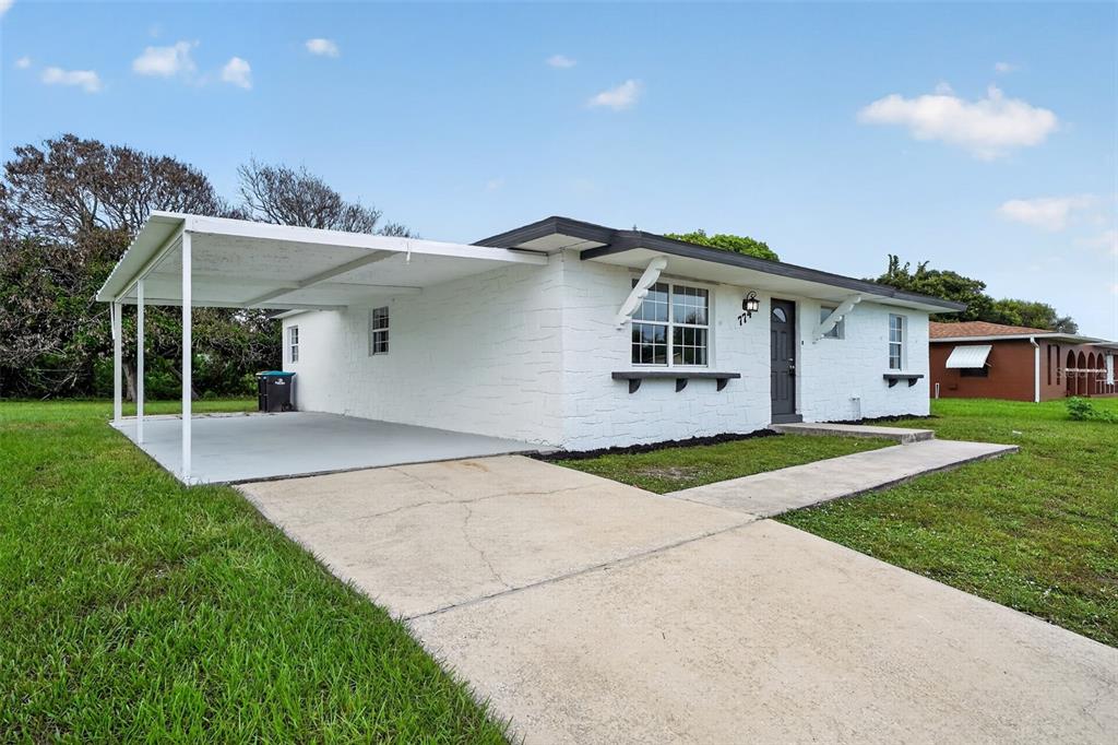 A white, single-story house features a concrete driveway, a carport, and a front walkway — 774 HAMPTON DRIVE NE, PALM BAY, FL
