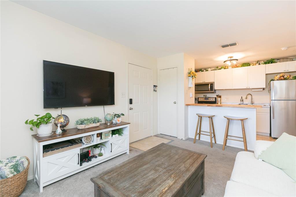 A living room with a television console, coffee table, and an open kitchen with stools — 1400 GANDY BOULEVARD N UNIT 507, ST PETERSBURG, FL