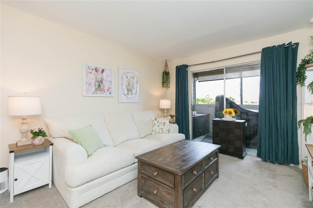 A living room features a white sofa, wooden coffee table, and sliding glass balcony doors — 1400 GANDY BOULEVARD N UNIT 507, ST PETERSBURG, FL
