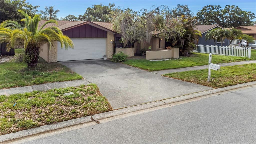 A single-story house with a white garage door, a concrete driveway, and palm trees — 107 COUNTRY VILLAS DRIVE, SAFETY HARBOR, FL
