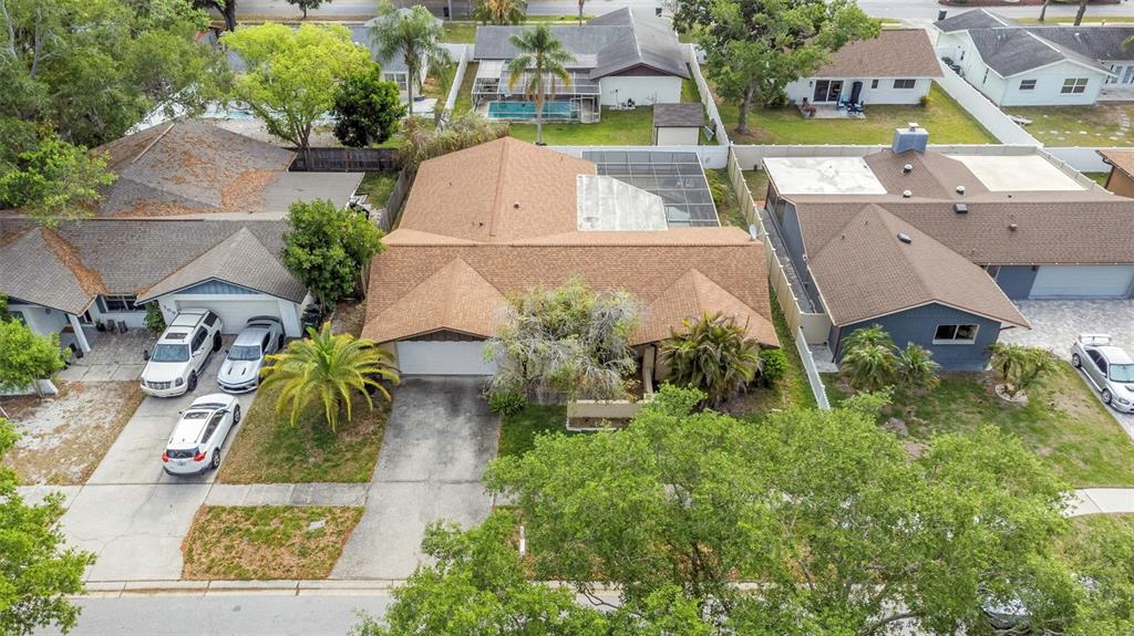 An aerial view shows a suburban house with a brown shingled roof and pool enclosure — 107 COUNTRY VILLAS DRIVE, SAFETY HARBOR, FL