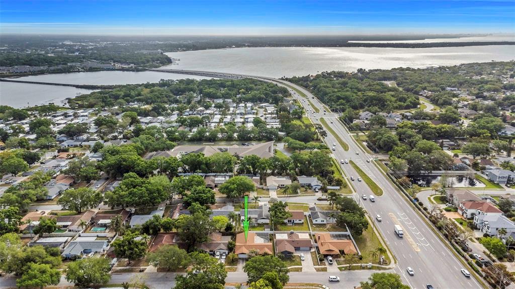 An aerial view shows a residential neighborhood with a green arrow pointing to a house — 107 COUNTRY VILLAS DRIVE, SAFETY HARBOR, FL