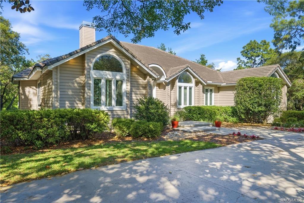 A single-story house with tan siding, a tile roof, and arched windows sits near trees — 3475 W WILD DUNES PLACE, LECANTO, FL