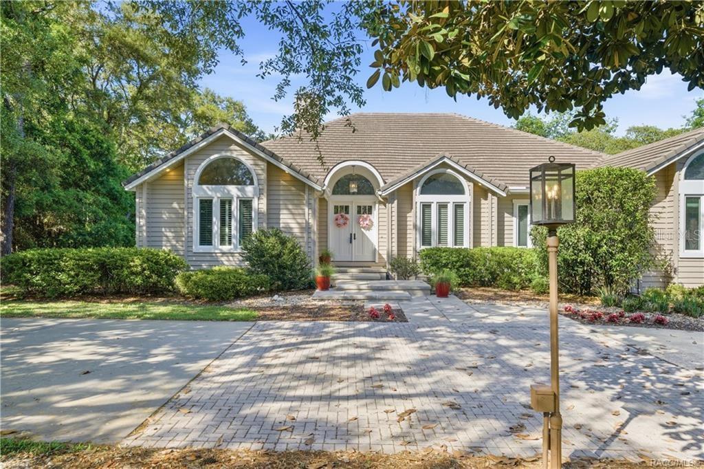 A single-story house with beige siding, a paved driveway, and an arched entryway — 3475 W WILD DUNES PLACE, LECANTO, FL
