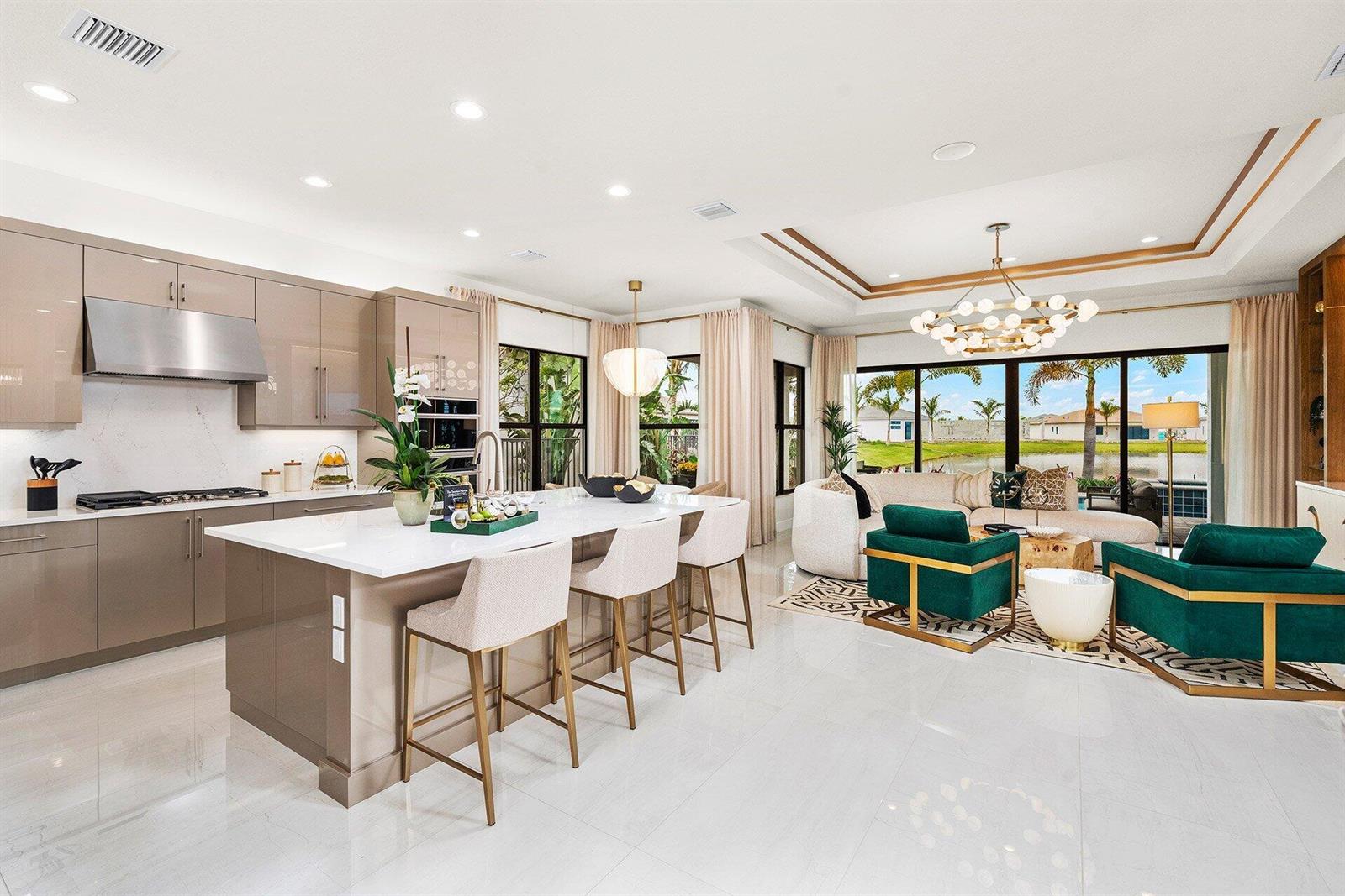 A modern open-concept kitchen and living area featuring a large island and emerald green chairs — 9123 Red Robin Lane, Boynton Beach FL 33473, BOYNTON BEACH, FL