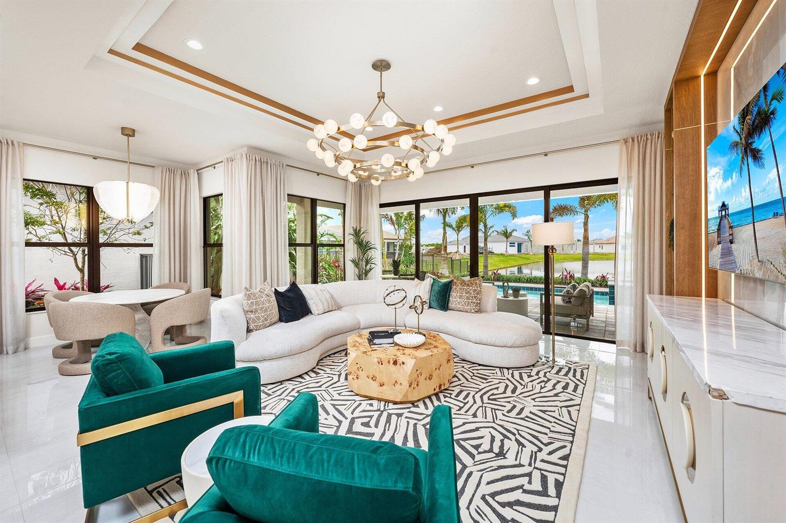 A bright living room features a curved white sofa, teal armchairs, and a pool view — 9123 Red Robin Lane, Boynton Beach FL 33473, BOYNTON BEACH, FL