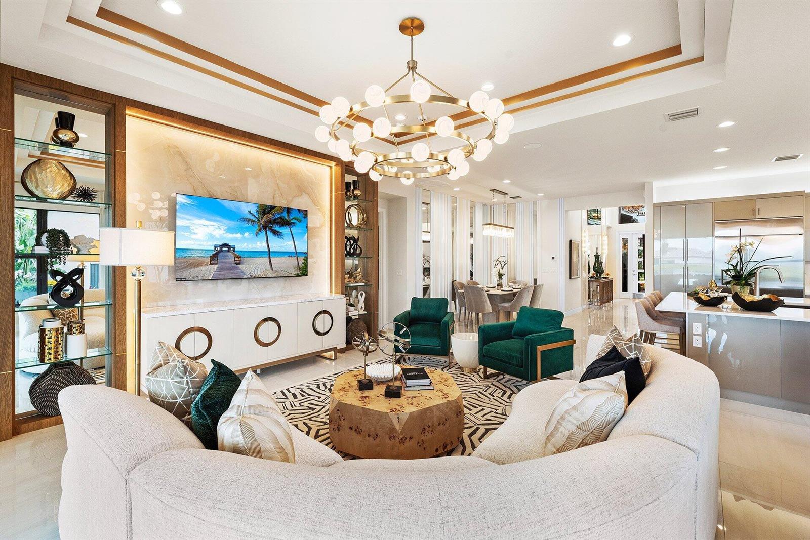 A modern living room features a curved sofa, green armchairs, and a large gold chandelier — 9123 Red Robin Lane, Boynton Beach FL 33473, BOYNTON BEACH, FL