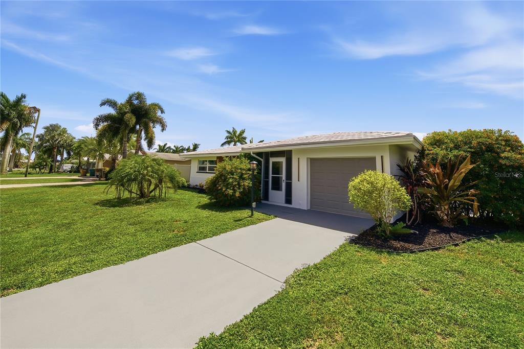 A single-story house with a gray garage door, a concrete driveway, and surrounding palm trees — 3106 SE 18TH PLACE, CAPE CORAL, FL