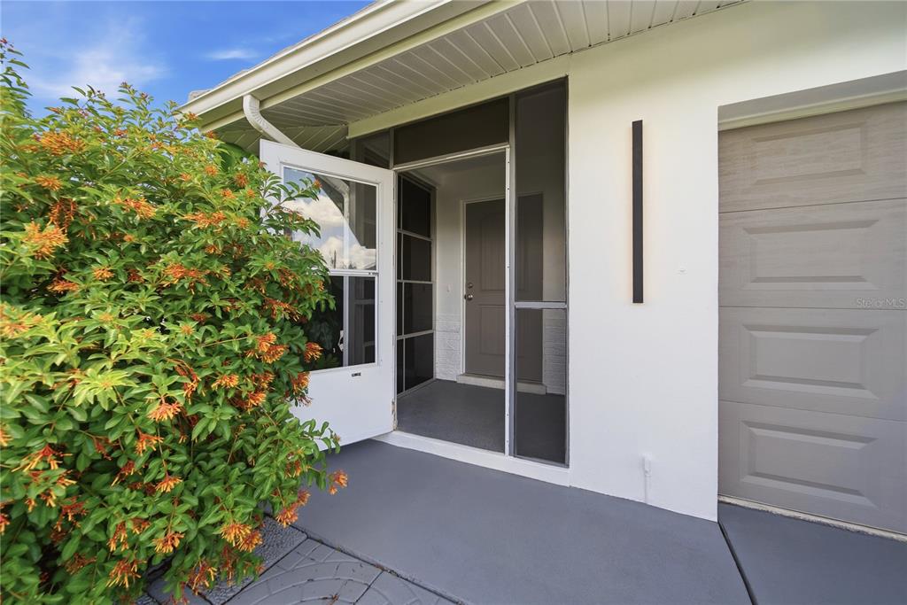 A house entrance with a screened porch, a white door, and a large flowering bush — 3106 SE 18TH PLACE, CAPE CORAL, FL