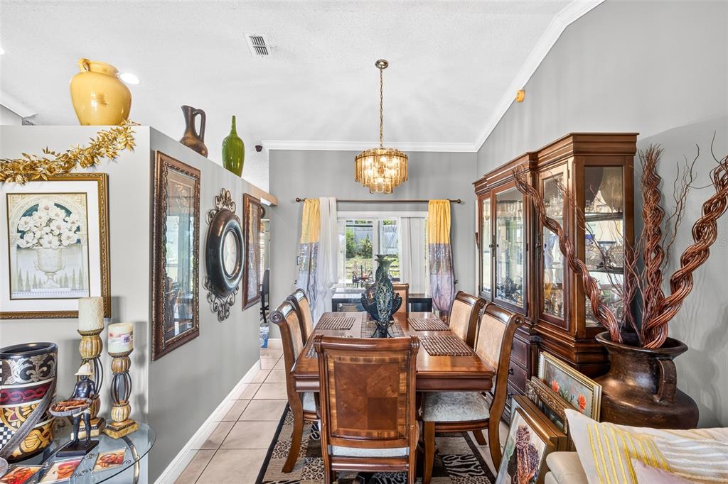 A dining room features a wooden table and chairs, a crystal chandelier, and a hutch — 6616 CORAL COVE DRIVE, ORLANDO, FL