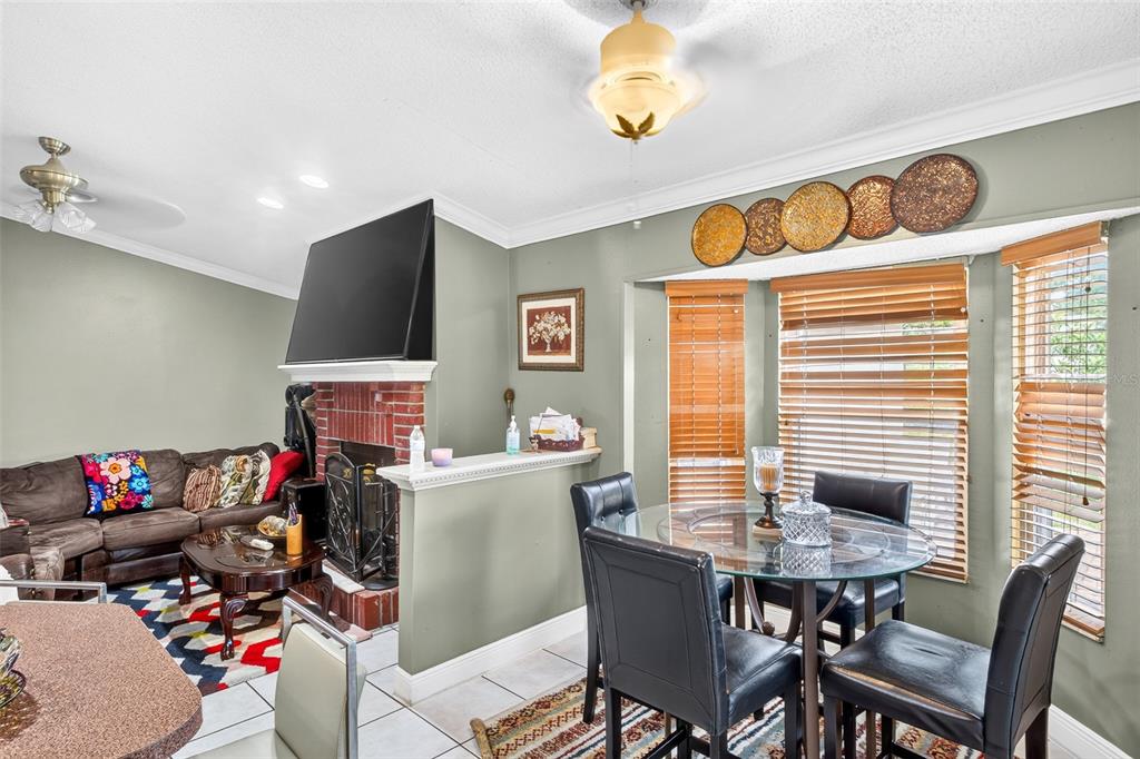 A living room with a brick fireplace and an adjacent dining area with a table — 6616 CORAL COVE DRIVE, ORLANDO, FL