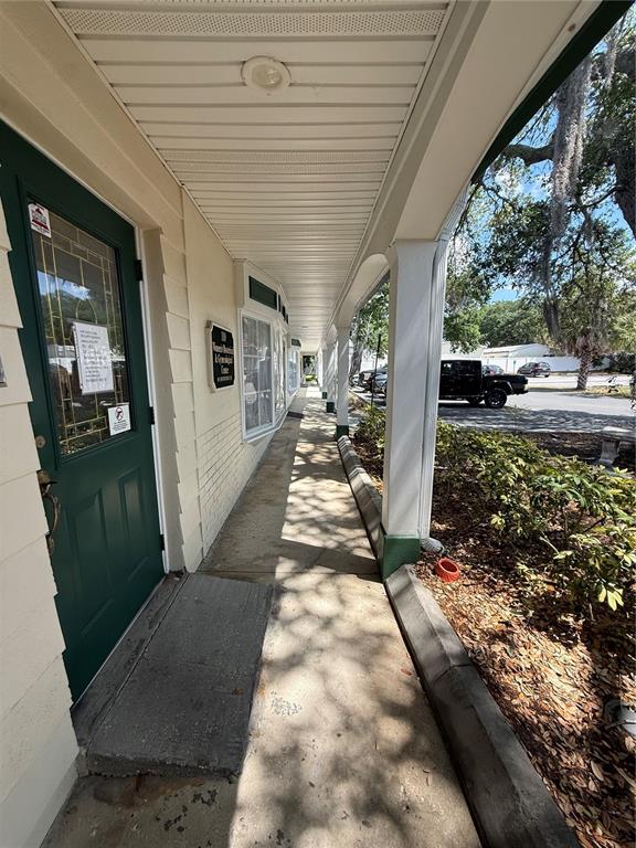 A covered concrete walkway runs along the side of a building with a green door — 28960 US HIGHWAY 19 N UNIT 110, CLEARWATER, FL