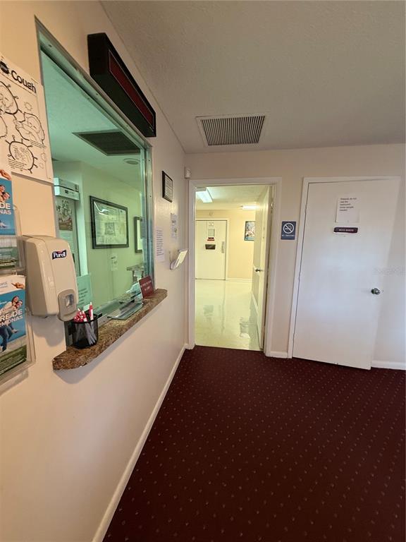 A reception window with a counter opens into a hallway with a white door — 28960 US HIGHWAY 19 N UNIT 110, CLEARWATER, FL