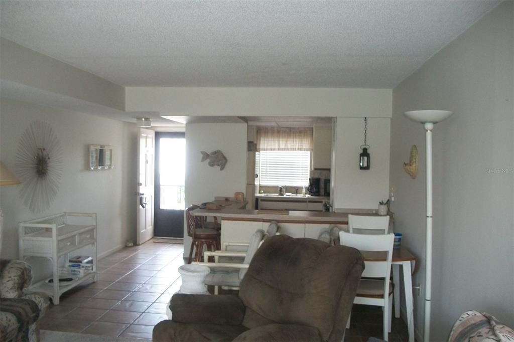 A living room with tile flooring leads to an open kitchen with a breakfast bar — 10540 77TH TERRACE UNIT 210, SEMINOLE, FL