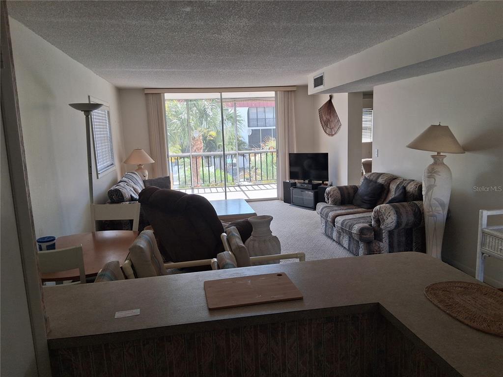 A living room and dining area feature carpeted floors, a balcony, and a kitchen counter — 10540 77TH TERRACE UNIT 210, SEMINOLE, FL