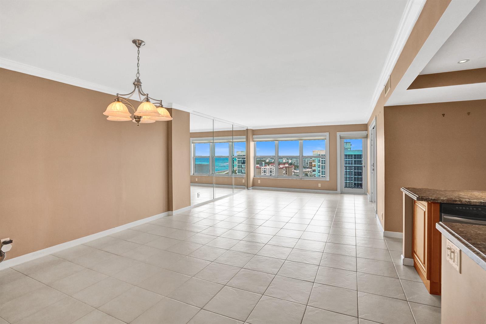 An empty dining area with beige walls, tile flooring, a chandelier, and mirrored wall panels — 405 N Ocean Boulevard # 1803, Pompano Beach FL 33062, POMPANO BEACH, FL