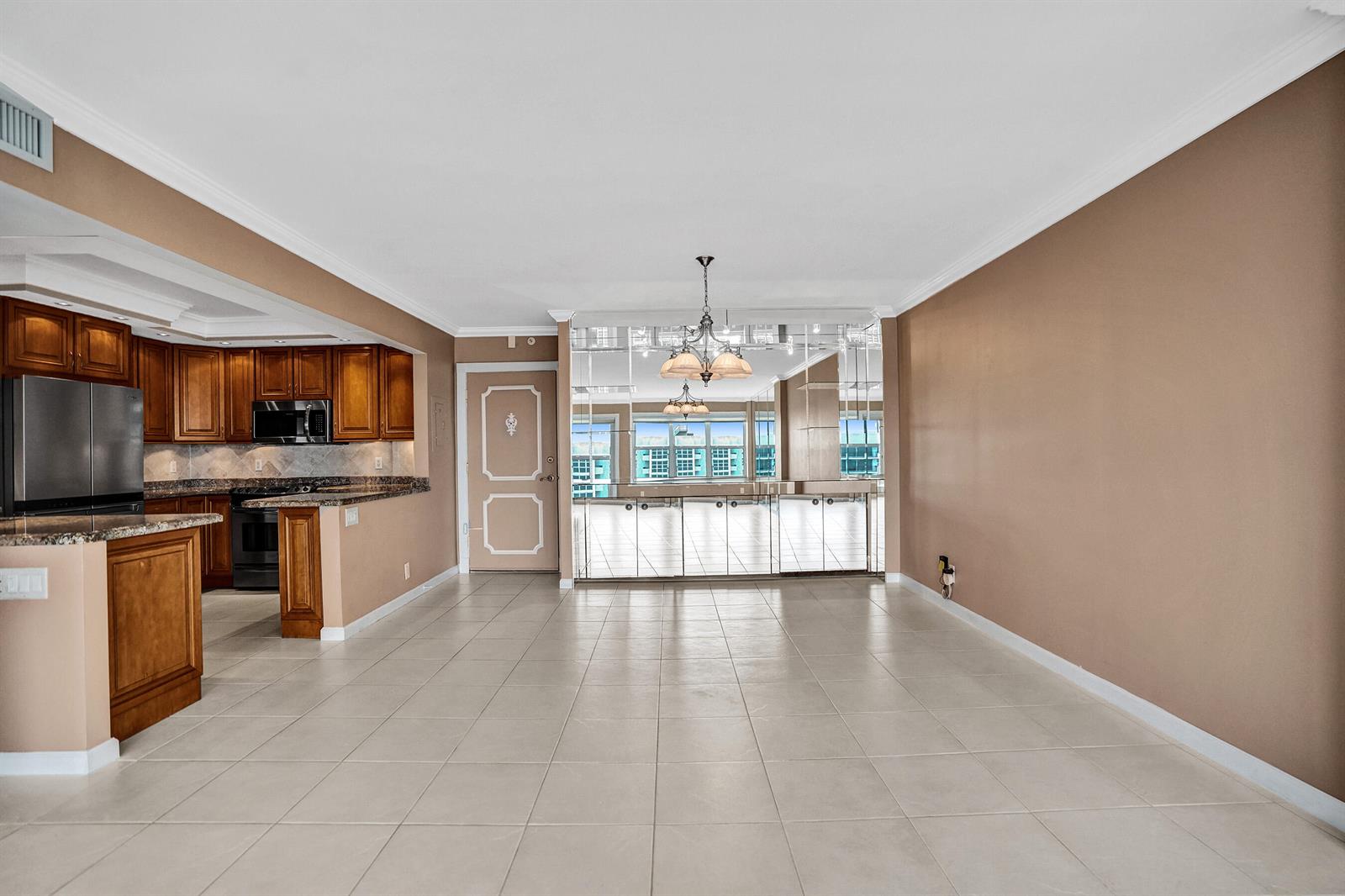 An open-concept dining and kitchen area with tile floors, wooden cabinets, and mirrored wall panels — 405 N Ocean Boulevard # 1803, Pompano Beach FL 33062, POMPANO BEACH, FL