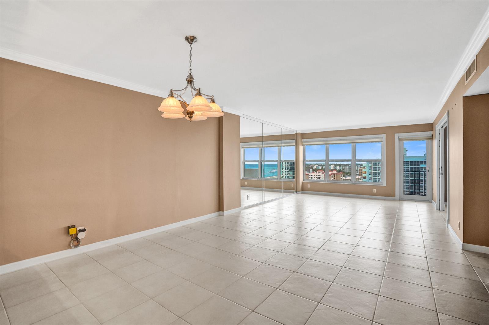 An empty room with beige walls, tile flooring, a chandelier, and floor-to-ceiling windows — 405 N Ocean Boulevard # 1803, Pompano Beach FL 33062, POMPANO BEACH, FL