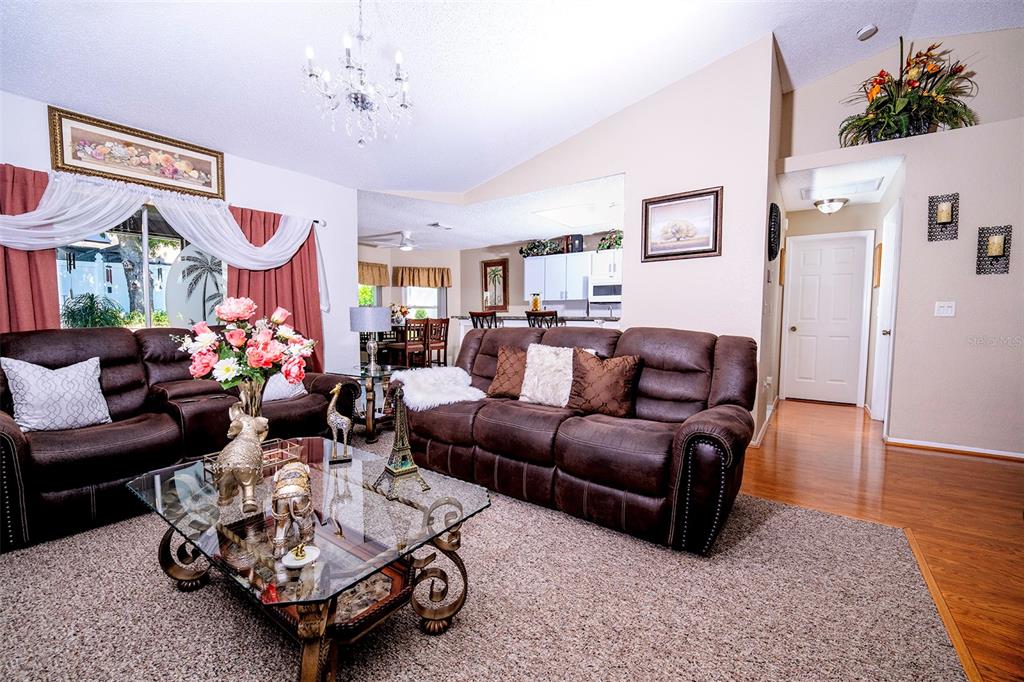 A living room features brown leather sofas, a glass coffee table, and a vaulted ceiling — 8128 GOLDEN BEAR LOOP, PORT RICHEY, FL