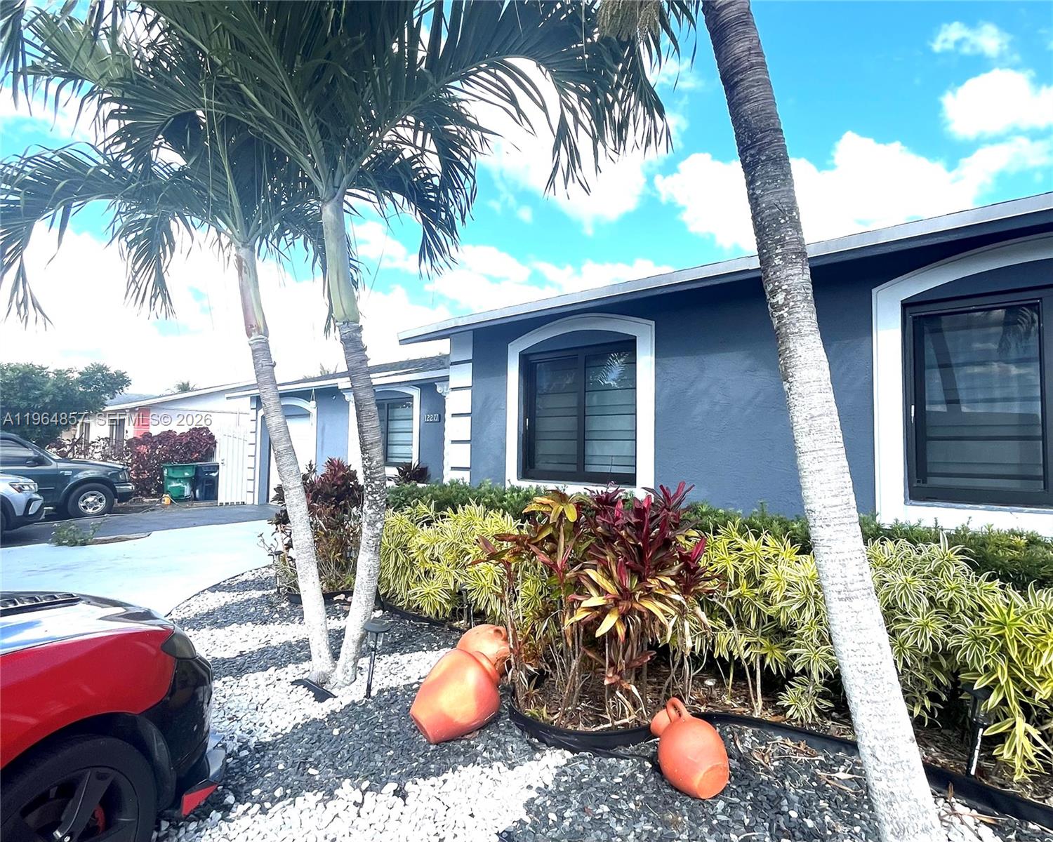 The exterior of a blue house features palm trees, landscaping, and decorative terracotta pots — 12271 SW 187th St, Miami FL 33177, MIAMI, FL