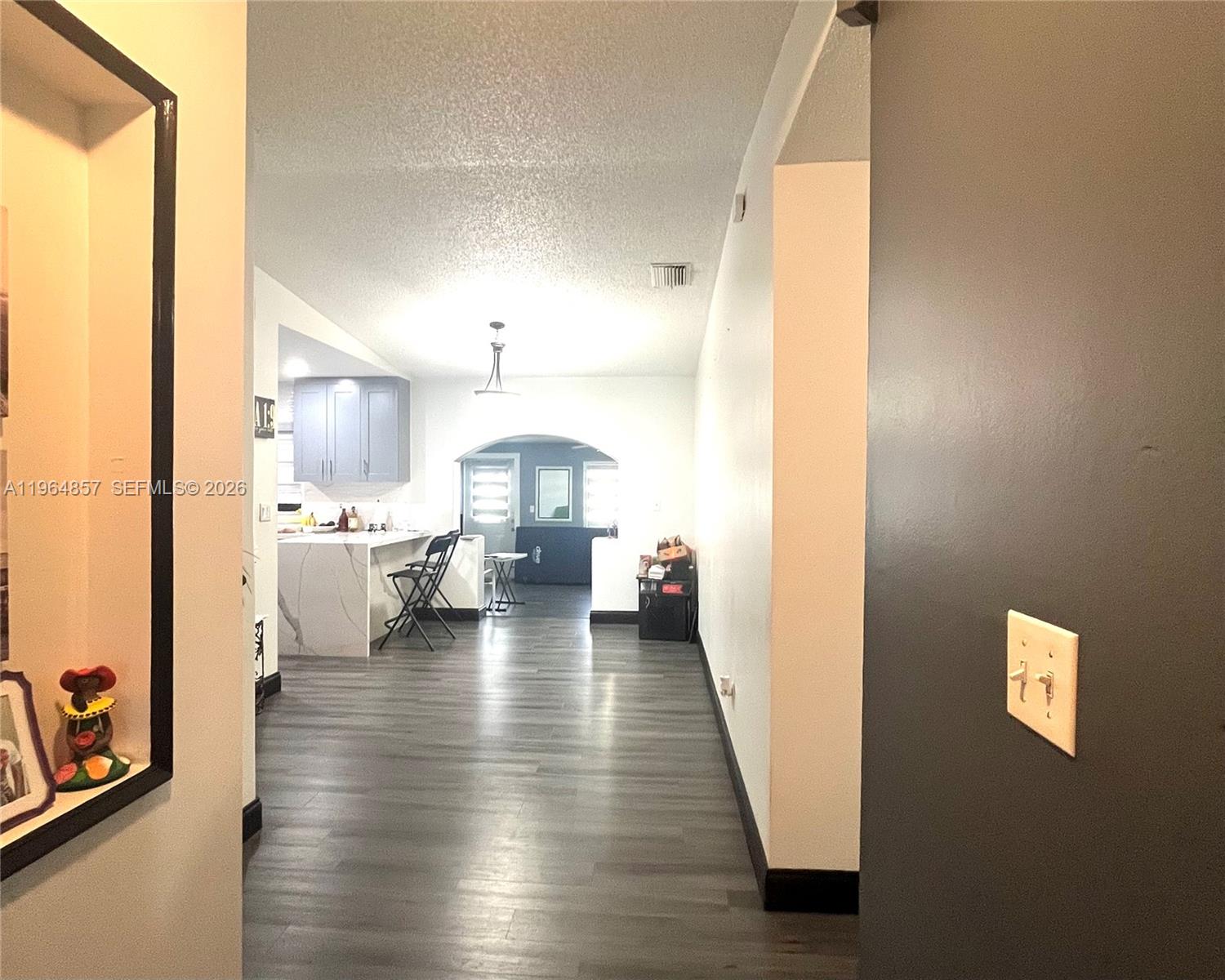 A hallway leads into an open-concept kitchen and living area with wood-look flooring — 12271 SW 187th St, Miami FL 33177, MIAMI, FL