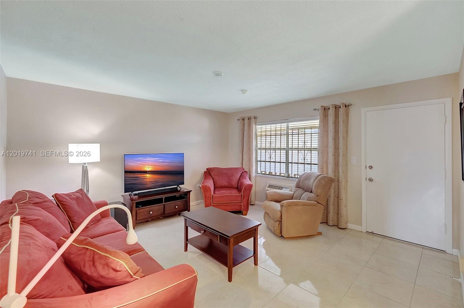 A living room features a red sofa, a matching armchair, a recliner, and a television — 17001 NE 13th ave # 306, Miami FL 33162, MIAMI, FL