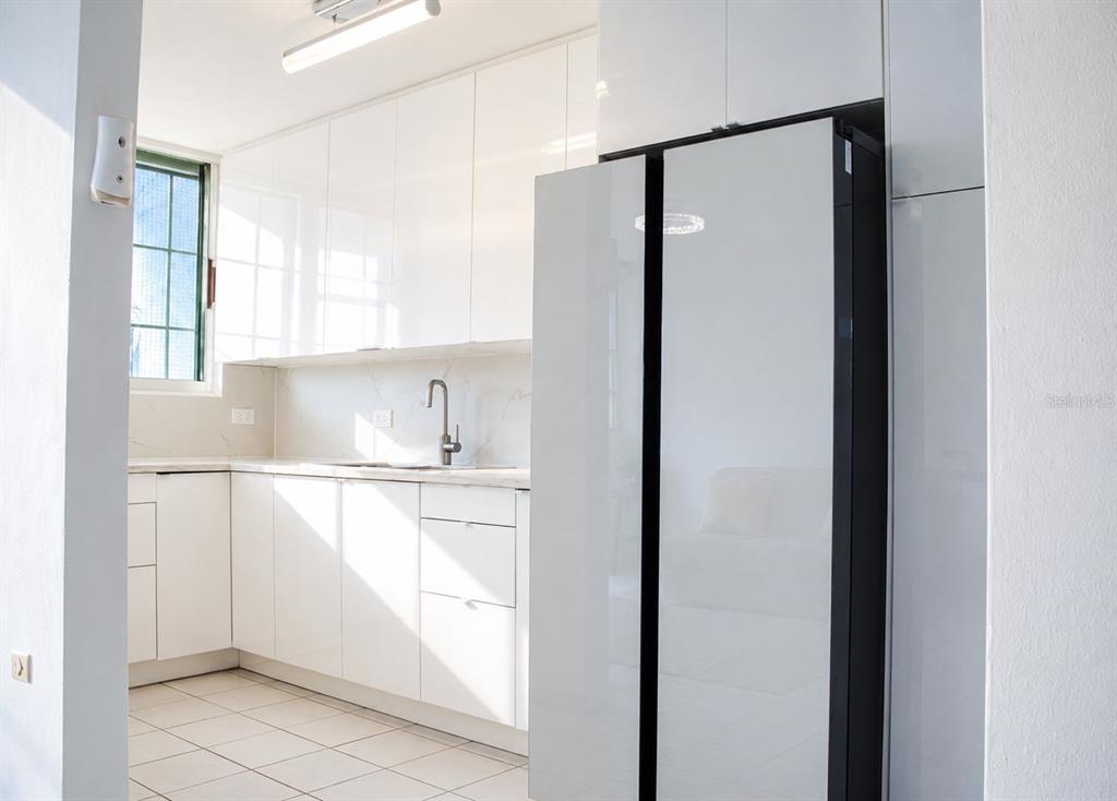 A modern kitchen features white cabinets, light countertops, a stainless steel faucet, and a refrigerator — BOULEVARD DEL RIO II, GUAYNABO, PR