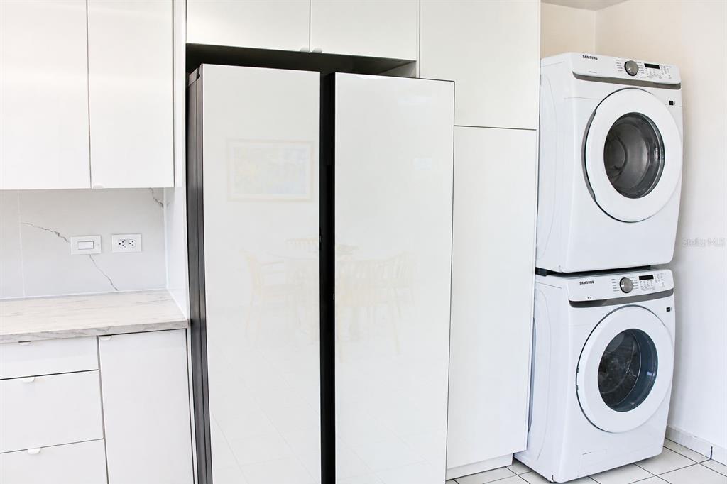 A modern kitchen features white cabinetry, a side-by-side refrigerator, and a stacked laundry unit — BOULEVARD DEL RIO II, GUAYNABO, PR