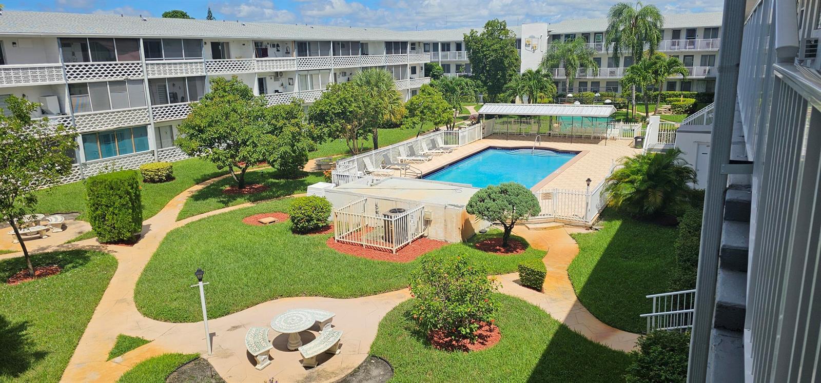 An elevated view of a residential courtyard featuring a swimming pool, lawn, and apartment buildings — 15610 NE 6th Avenue # 37b, Miami FL 33162, MIAMI, FL
