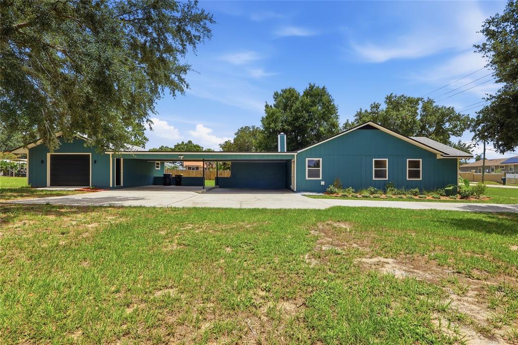 A teal single-story house with a large attached carport and a detached garage — 6028 YARBOROUGH LANE, LAKELAND, FL