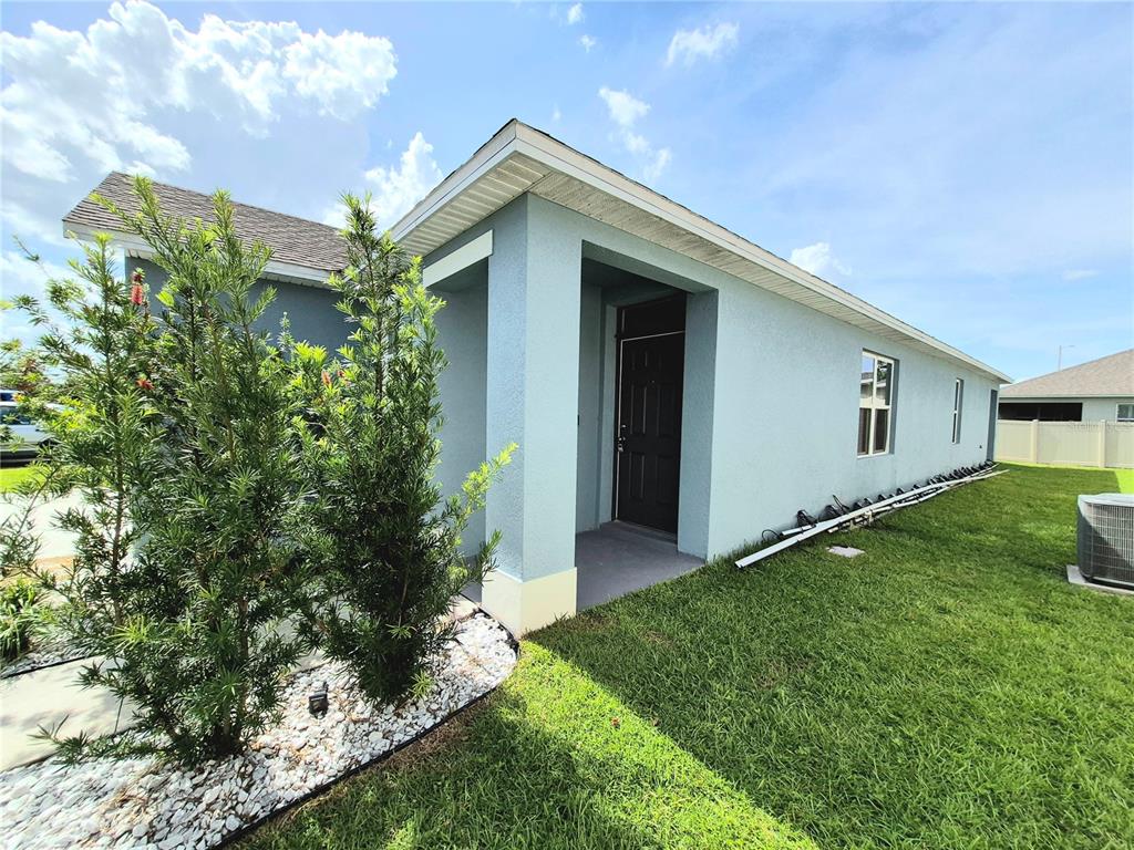 A light blue house exterior features a front entryway, a dark door, and landscaping — 2375 BRASSIE COURT, WINTER HAVEN, FL
