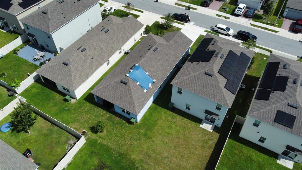 An aerial view shows several suburban houses with fenced backyards and roofs featuring solar panels — 2375 BRASSIE COURT, WINTER HAVEN, FL