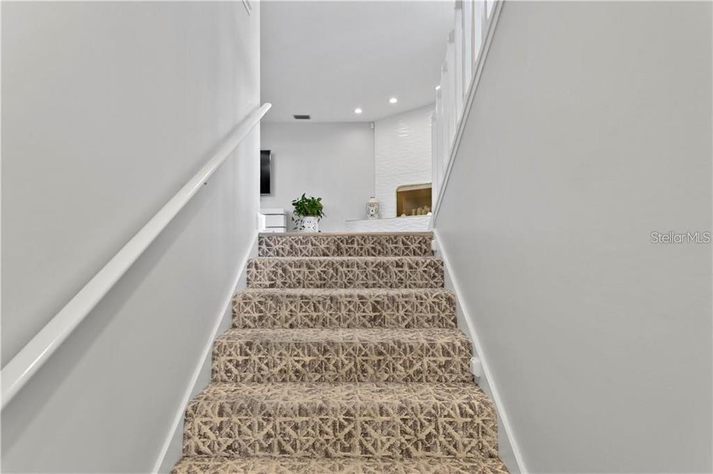 A staircase with patterned carpet leads up to a bright room with a fireplace — 11722 CURRIE LANE UNIT J1, LARGO, FL