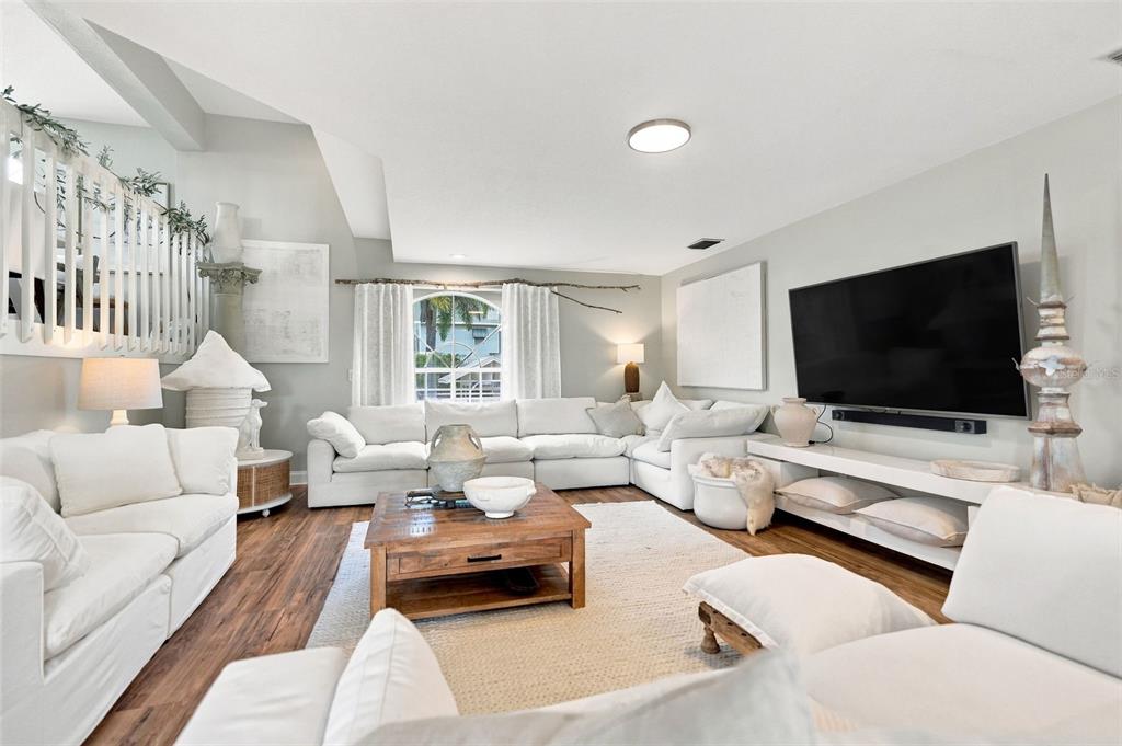 A living room features white sofas, a wooden coffee table, and a large wall-mounted television — 11722 CURRIE LANE UNIT J1, LARGO, FL