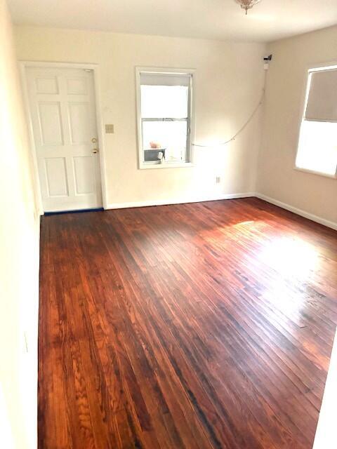 An empty room features dark hardwood flooring, a white door, and two windows — 44 SW 5th Street, Dania Beach FL 33004, DANIA BEACH, FL