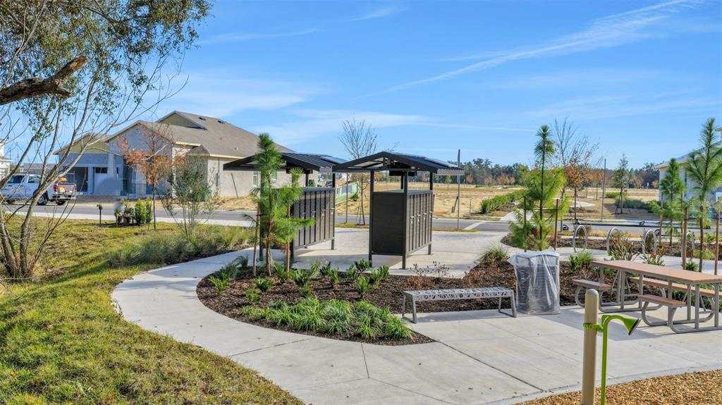 A neighborhood outdoor area featuring mailboxes, a picnic table, and a bench on concrete paths — 5978 FLOWERING CHERRY BEND, WINTER GARDEN, FL