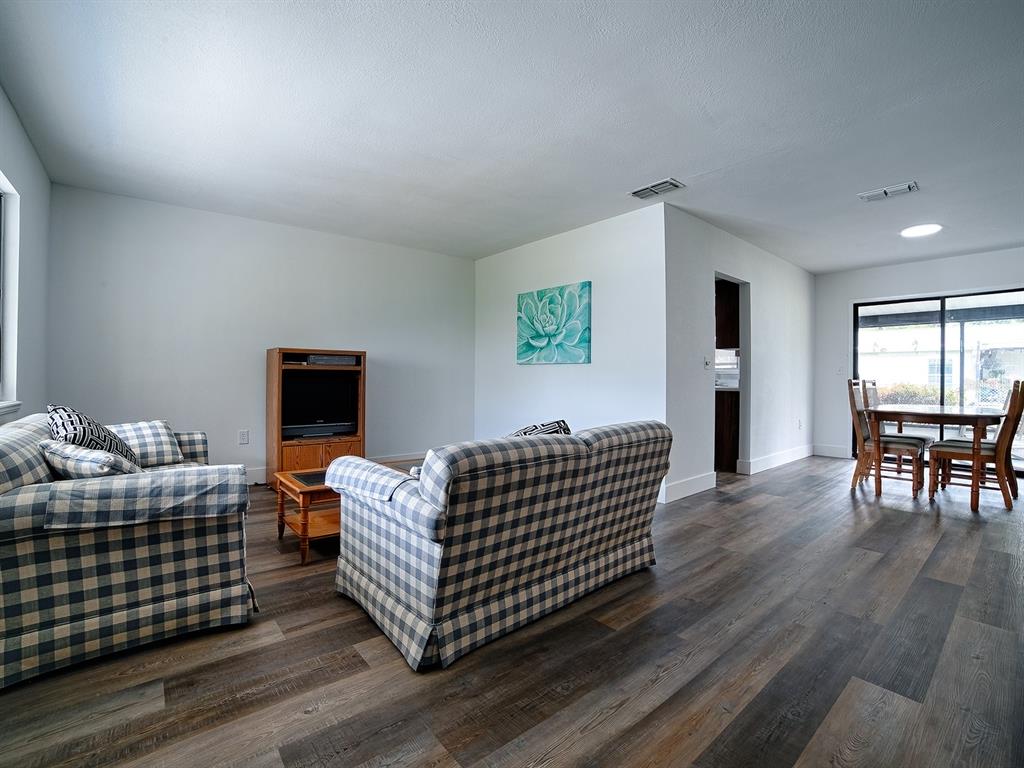 A living room with plaid sofas, wood-look flooring, and a dining area near sliding doors — 9115 SW 102ND LANE, OCALA, FL