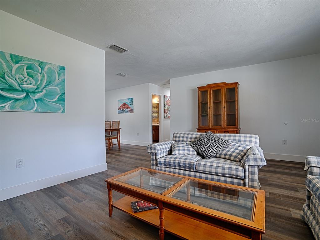A living room features a plaid sofa, a wooden coffee table, and wood-look flooring — 9115 SW 102ND LANE, OCALA, FL