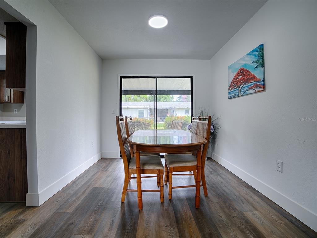 A dining area with wood-look flooring, a glass-topped table, four chairs, and a sliding glass door — 9115 SW 102ND LANE, OCALA, FL