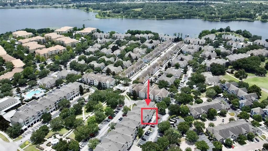 This aerial view shows a residential complex with townhomes surrounding a central park area — 6412 QUEENS BOROUGH AVENUE UNIT 313, ORLANDO, FL
