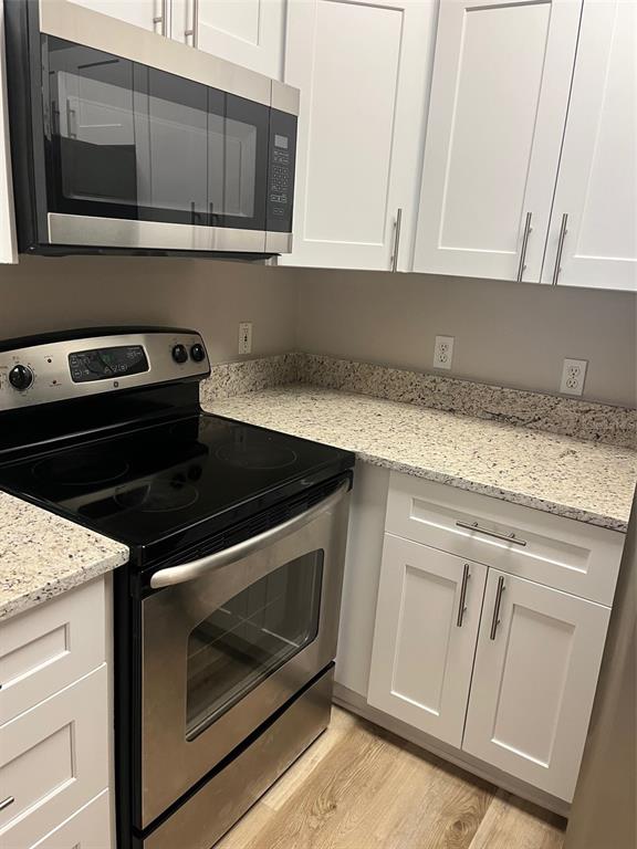 A kitchen features white cabinets, stainless steel appliances, and granite countertops — 6412 QUEENS BOROUGH AVENUE UNIT 313, ORLANDO, FL