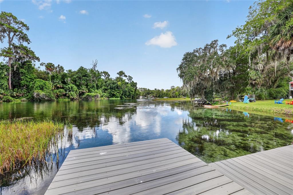 A wooden dock overlooks a clear river surrounded by lush trees and grassy banks — 9275 SW 186TH TERRACE, DUNNELLON, FL