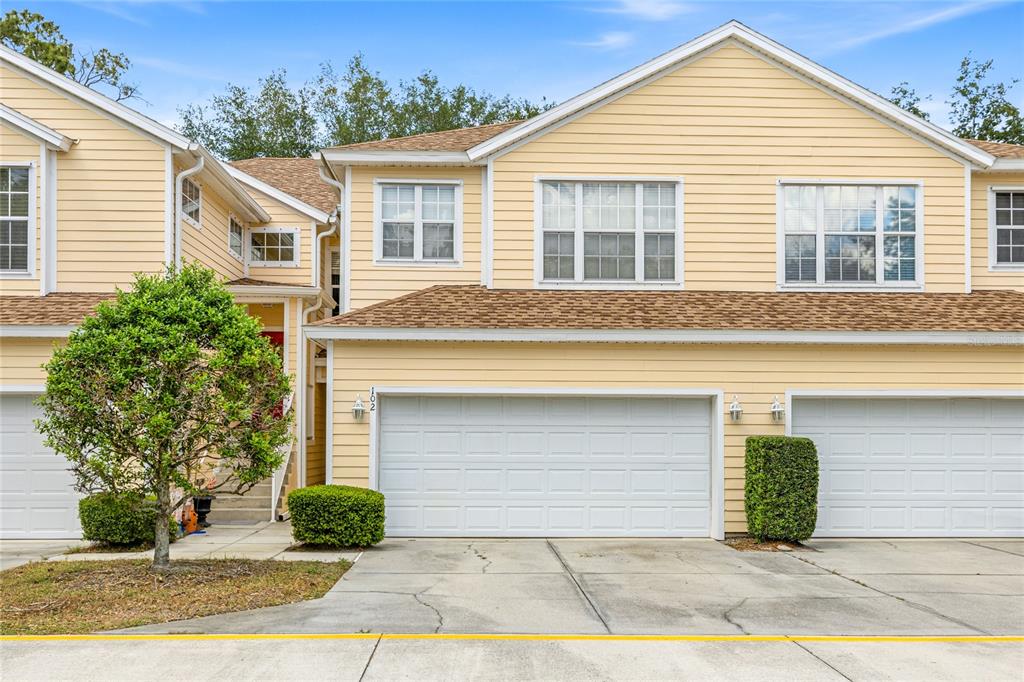 A two-story yellow townhouse features a two-car garage and a small front garden — 6216 ROSEFINCH COURT UNIT 102, LAKEWOOD RANCH, FL
