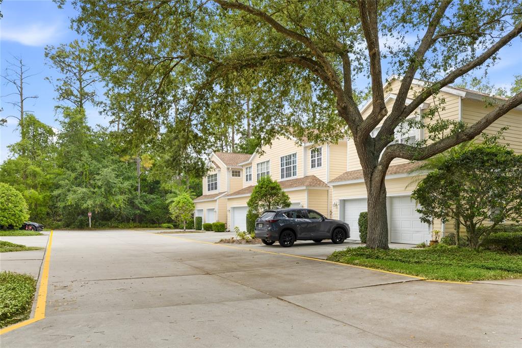 A row of yellow townhouses with attached garages and a parked car in the driveway — 6216 ROSEFINCH COURT UNIT 102, LAKEWOOD RANCH, FL