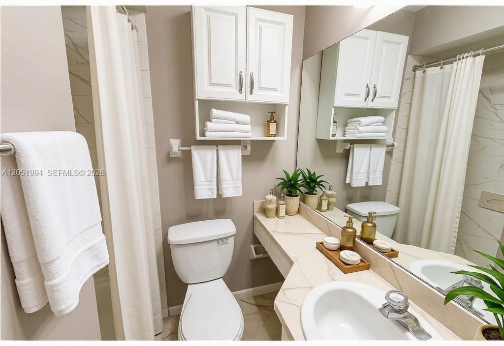 A bathroom features a white vanity, a toilet, a wall-mounted cabinet, and a shower curtain — 606 S Albany Ave # 0, Tampa FL 33606, TAMPA, FL