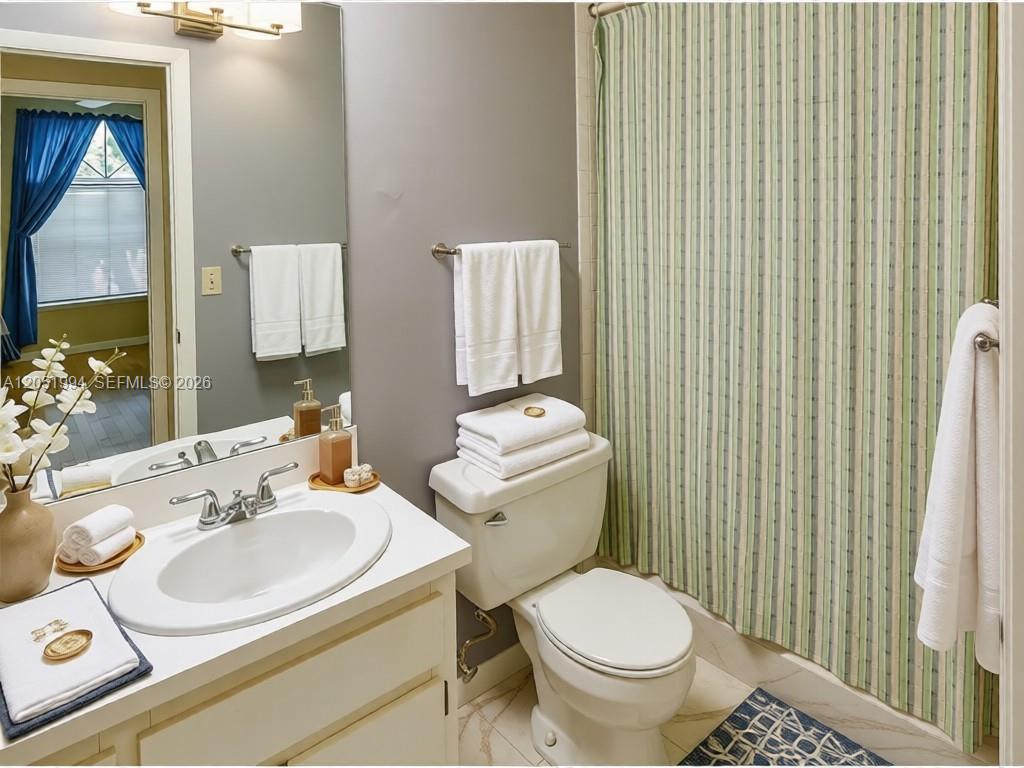 A bathroom features a white vanity, a toilet, and a green striped shower curtain — 606 S Albany Ave # 0, Tampa FL 33606, TAMPA, FL