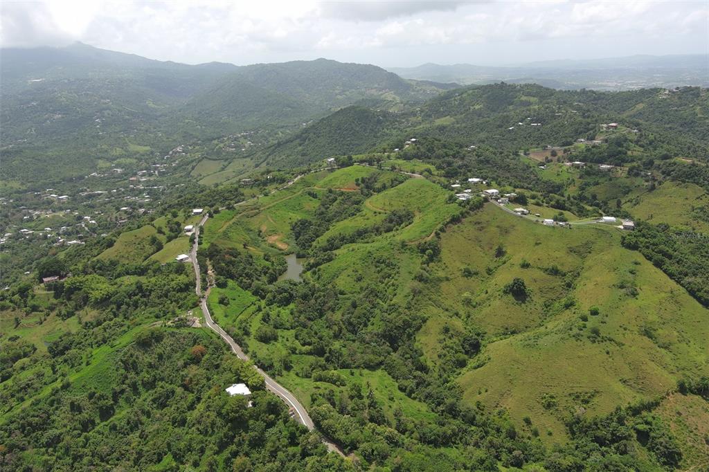 An aerial view shows a winding road through a lush, hilly landscape with scattered houses — FINCA MORALES BO. BARRAZAS, CAROLINA, PR