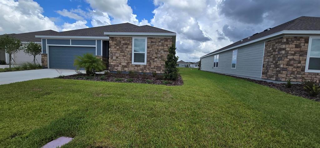 A single-story house with a stone facade, blue siding, and a two-car garage — 5543 MORANT BAY PATH, KISSIMMEE, FL