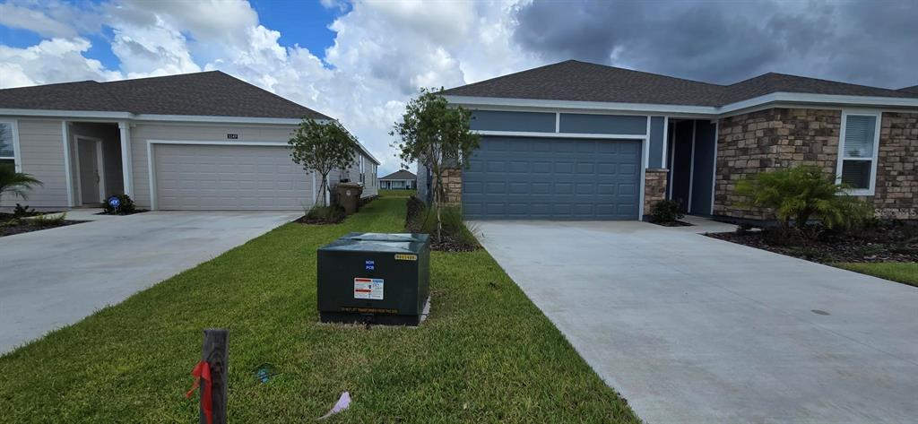 Two single-story suburban houses with attached garages and a utility transformer in the front yard — 5543 MORANT BAY PATH, KISSIMMEE, FL