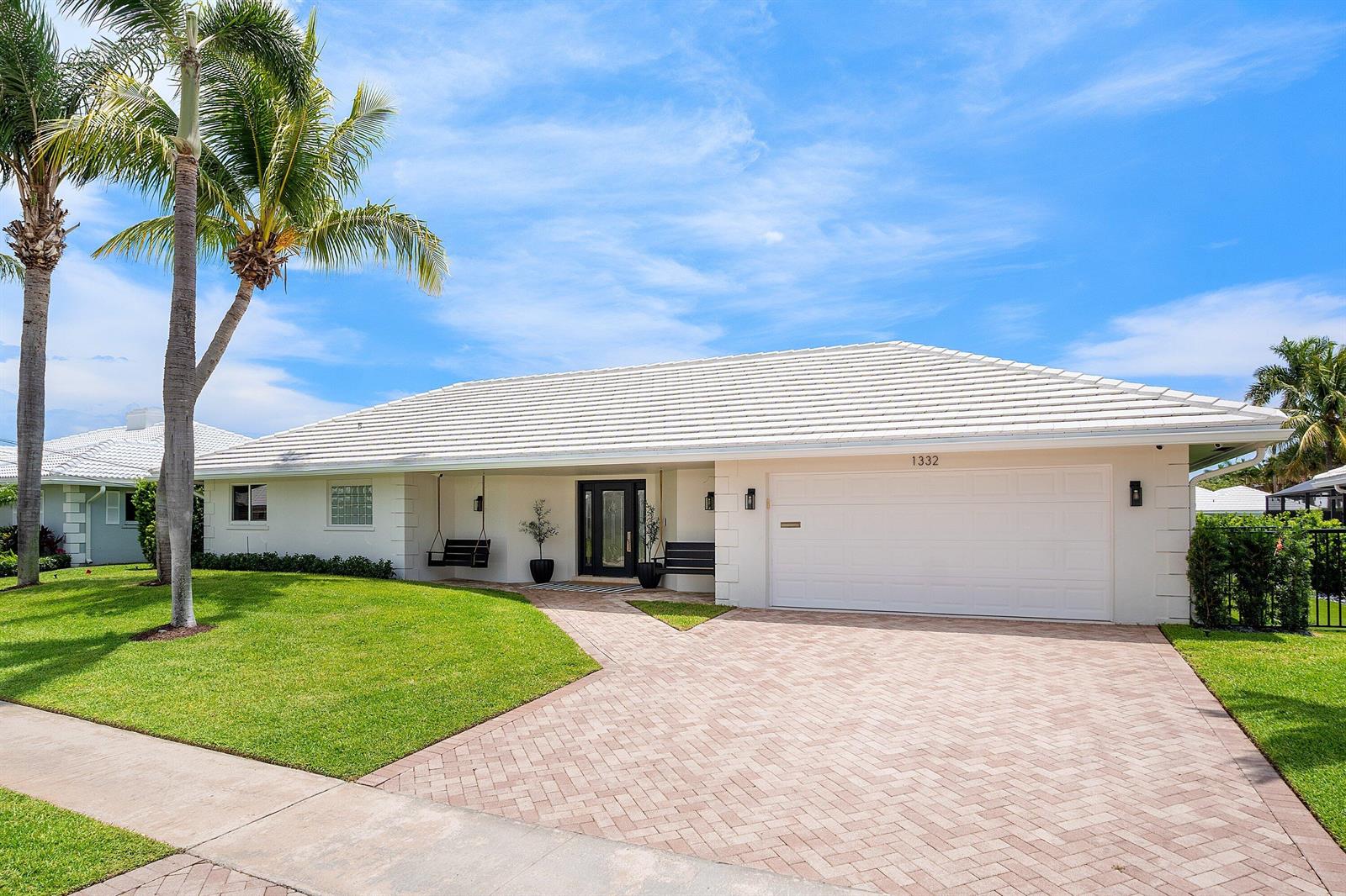 A white single-story house with a tiled roof, palm trees, and a paved driveway — 1332 SW Tamarind Way, Boca Raton FL 33486, BOCA RATON, FL